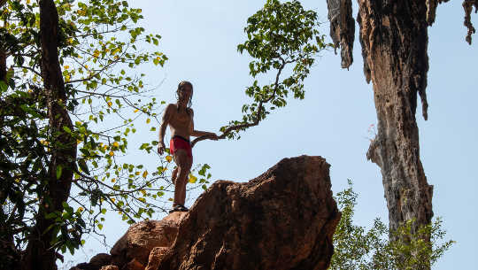 A Positive Way Forward Is Possible Even in the Darkest Times a young boy climbing to the top of a rock formation